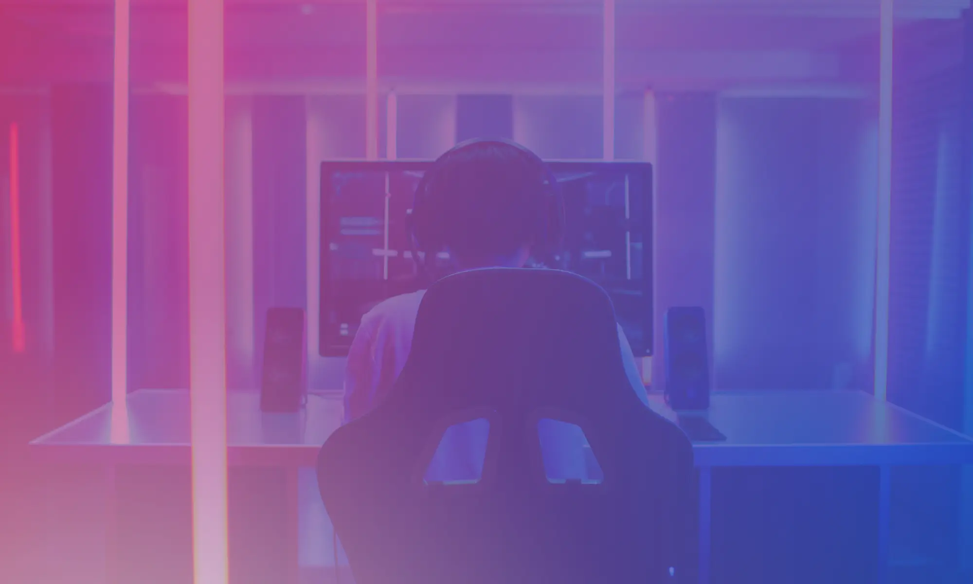 Person sitting at a computer in a warmly lit room, seen from behind"